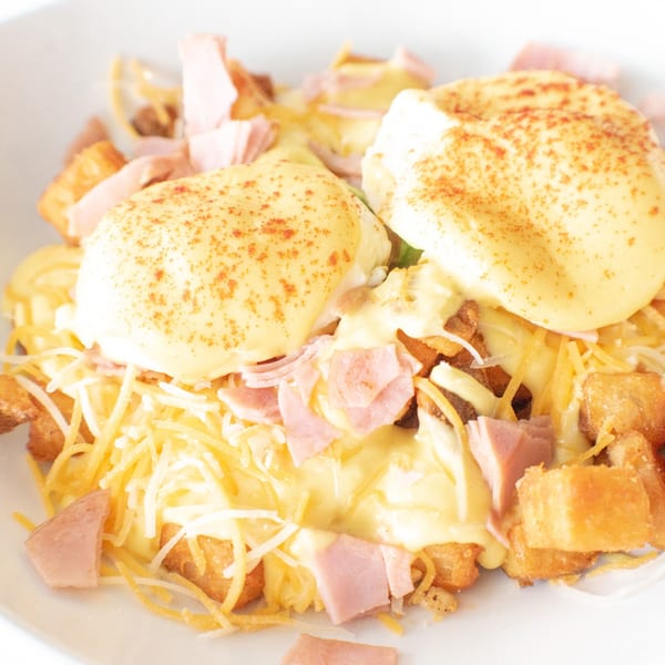 The Easy Egg's breakfast poutine with two poached eggs, hollandaise, ham, cheese, and crispy potatoes.